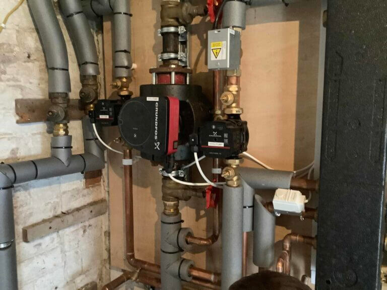 Detailed close-up of professional central heating system pipework, pumps, and valves