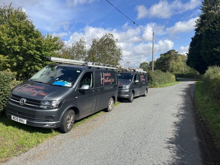 Two Hereford Heating service vans parked along a rural countryside road