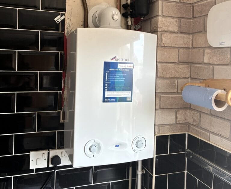 Large Worcester Bosch Greenstar boiler installation on a exposed brick and black tiled wall