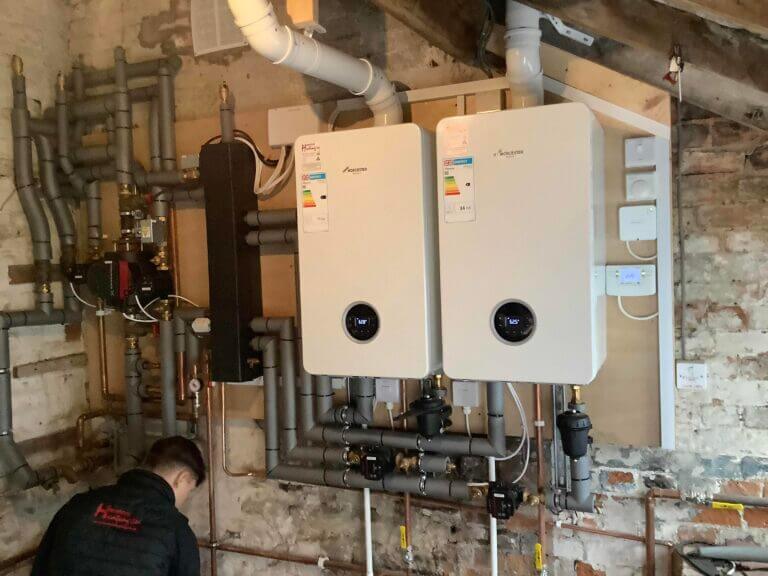 A complex, neat plant room installation showing two gas boilers running in cascade with detailed pipework