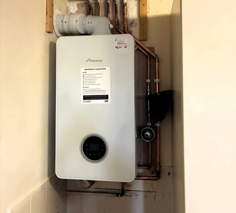 A Worcester Bosch boiler installed in a tight utility room corner with exposed copper pipework