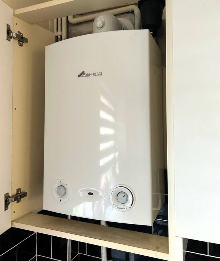 A compact boiler neatly installed inside a standard white kitchen cupboard
