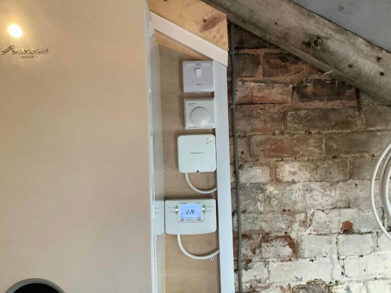 A smart wireless central heating thermostat mounted on a wooden support column