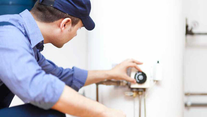 Heating engineer adjusting the control dial on a home heating system